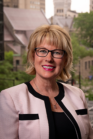 Patricia Galloway, woman with chin length blond hair, glasses and wearing a pink suit 